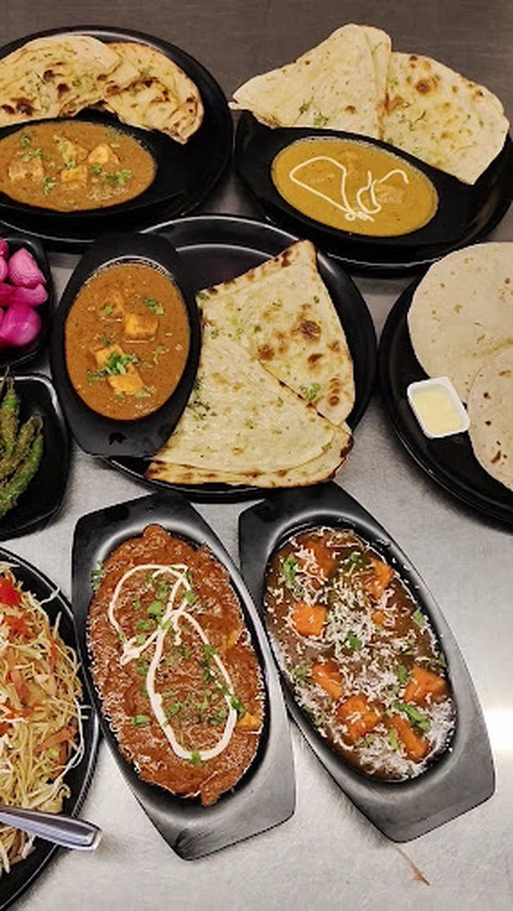 Paneer curries, naan and rice on a table at Da Punjabi Dhaba