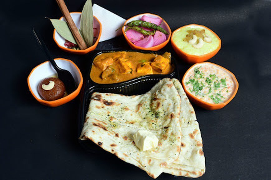 Punjabi thali with paneer curry, butter naan, pickled onions and sides at Da Punjabi Dhaba